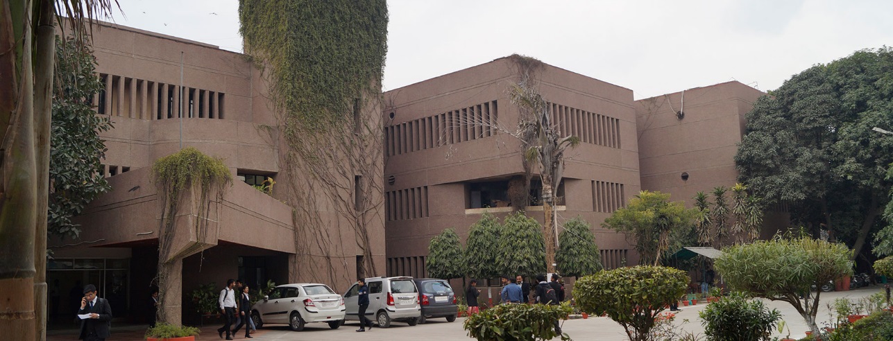 The concrete facade of the Institute of Hotel Management, Lucknow, framed by trees.